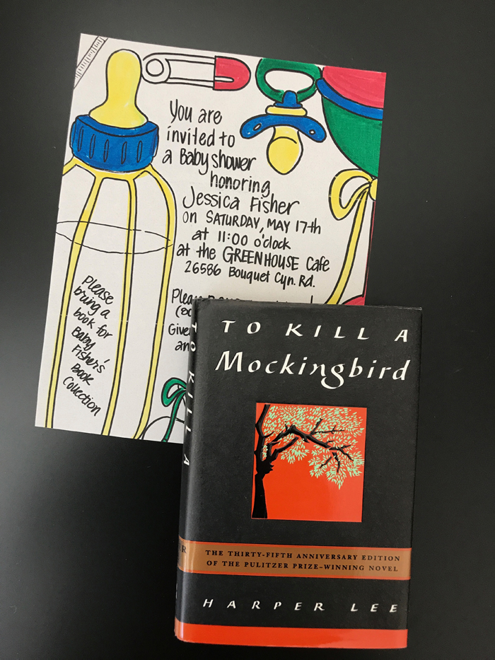 baby shower invitation next to a copy of To Kill a Mockingbird.