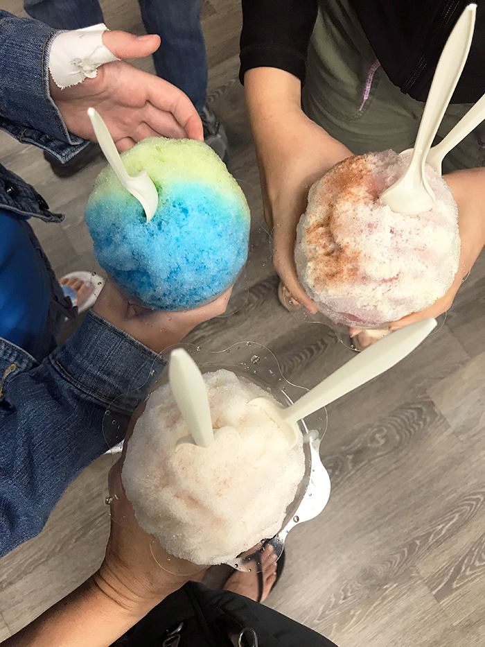 hands holding different flavors of shave ice