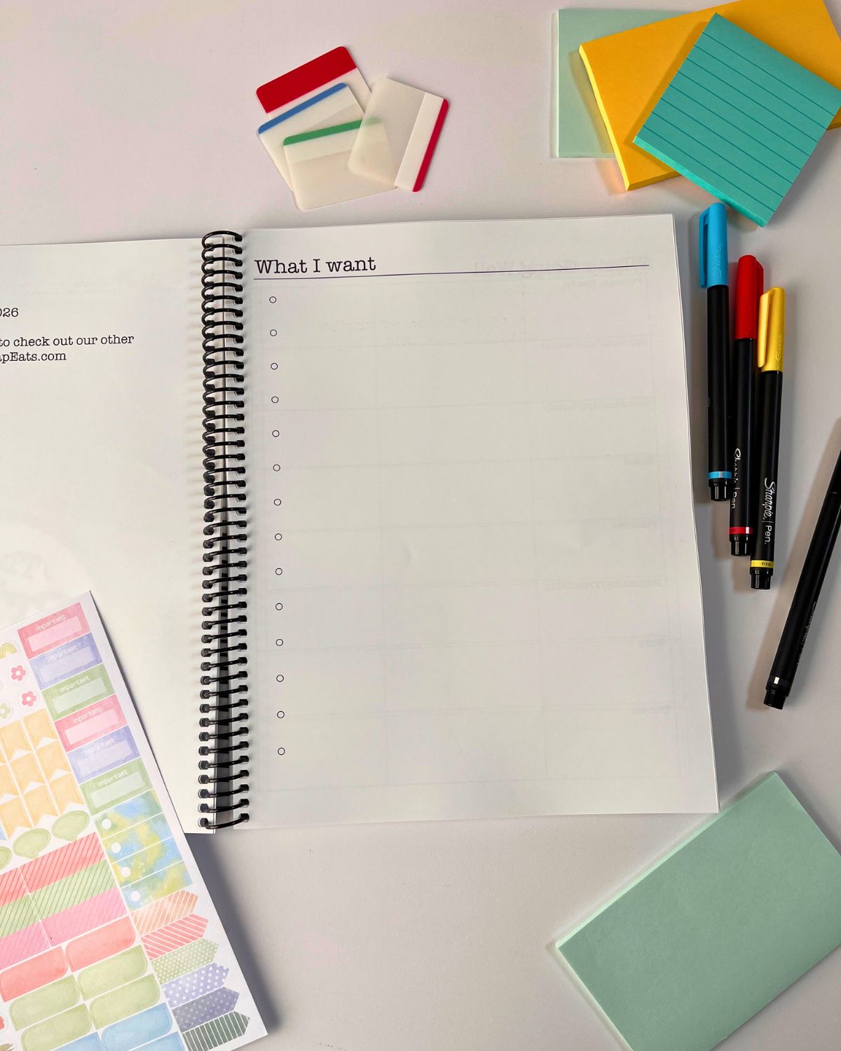 planner open to what i want page with planner accessories on table nearby.