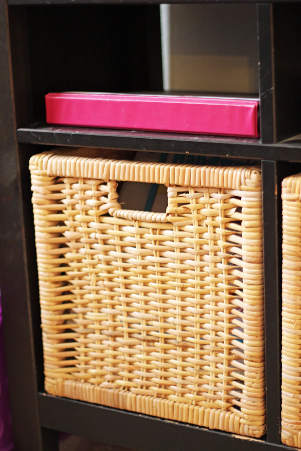 basket in a cubby with pink binder on shelf above.