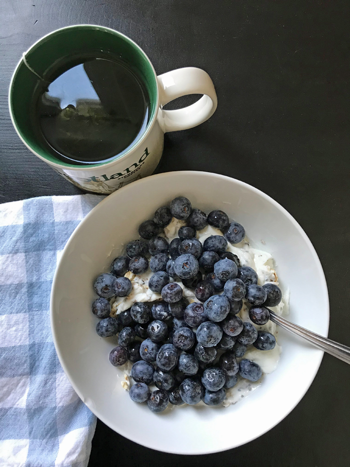 cup of tea with bowl of berries and yogurt