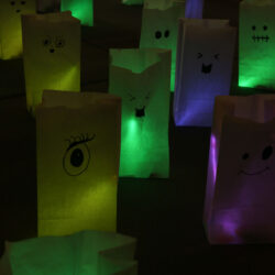 ghost halloween treat bags glowing purple, pink, yellow, and green.
