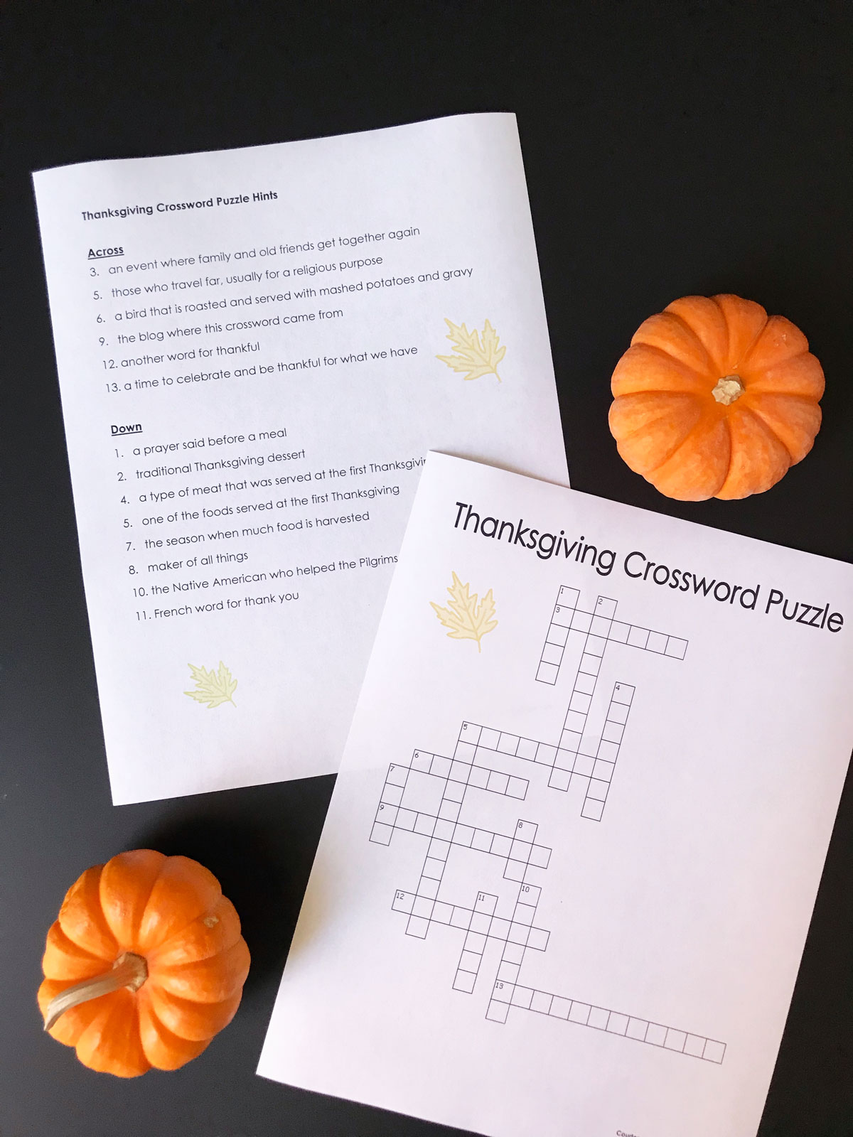 printed thanksgiving crossword puzzle and answer key on black table with mini pumpkins.