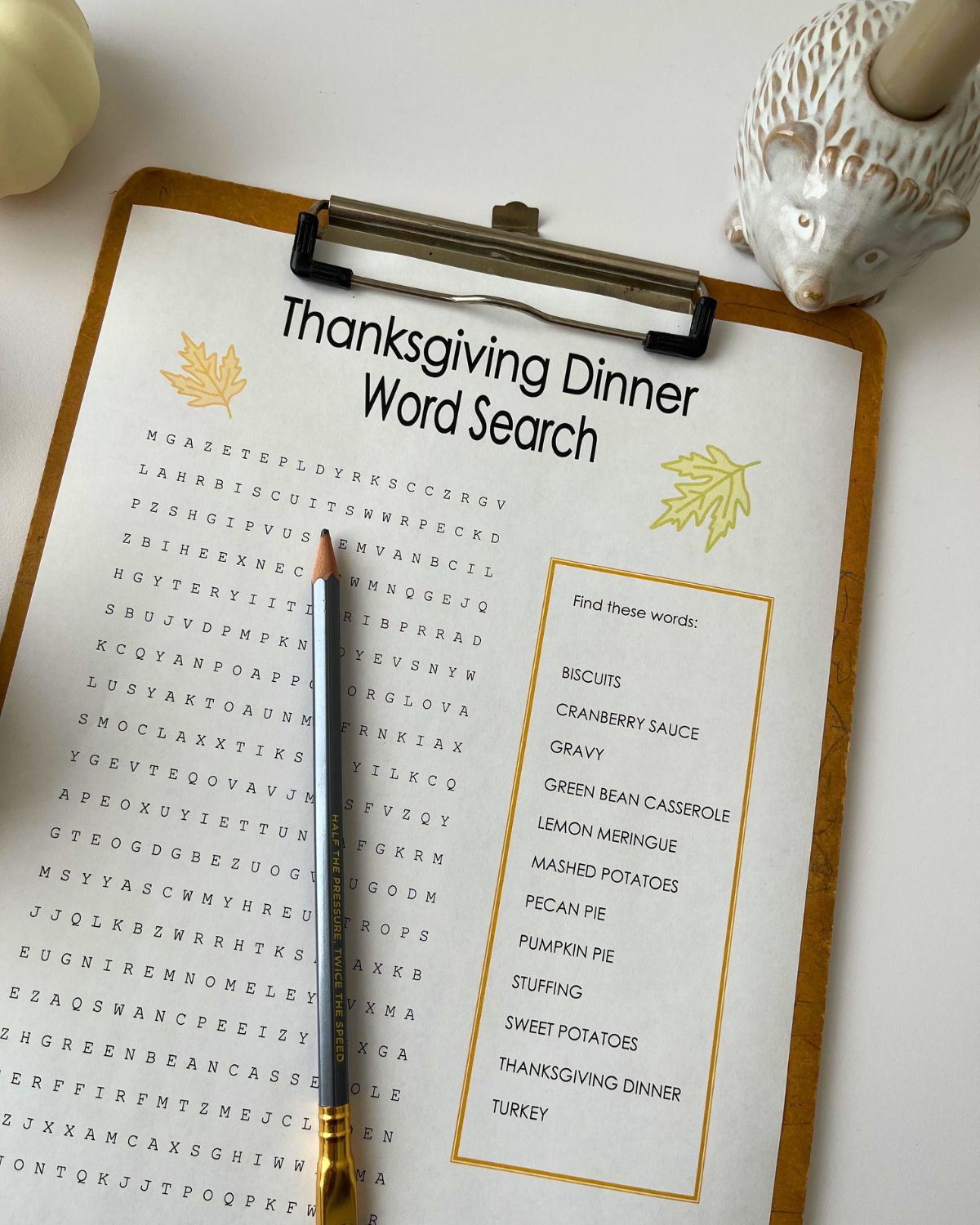 thanksgiving word search on clipboard with pencil and fall decor nearby.