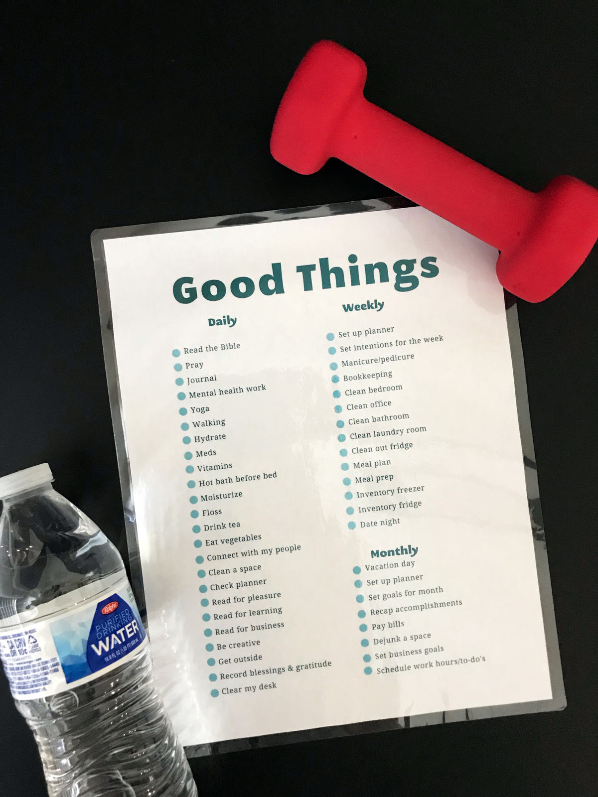 self care checklist on black table with small weight and a water bottle.