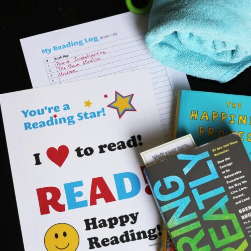 close up of reading log printable next to books and beach towel.