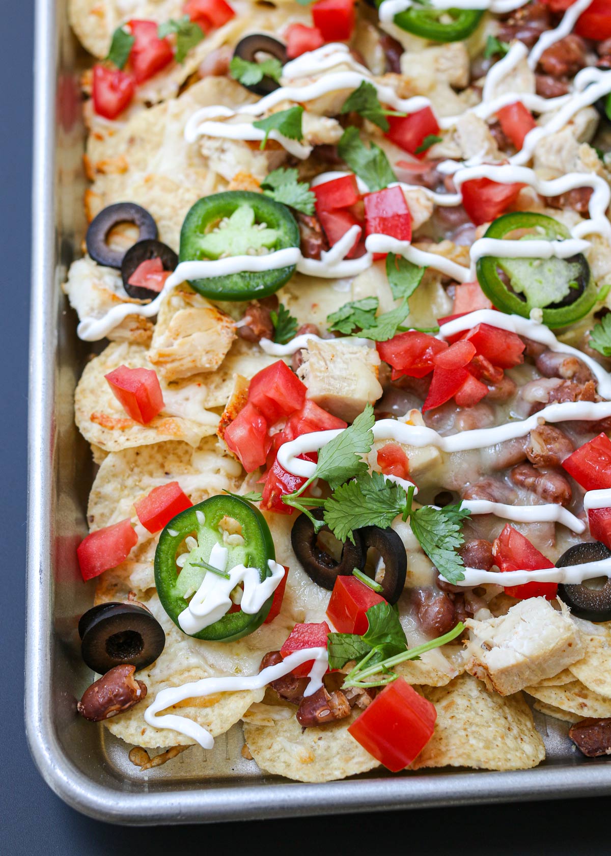 close up of sheet pan nachos loaded with toppings.