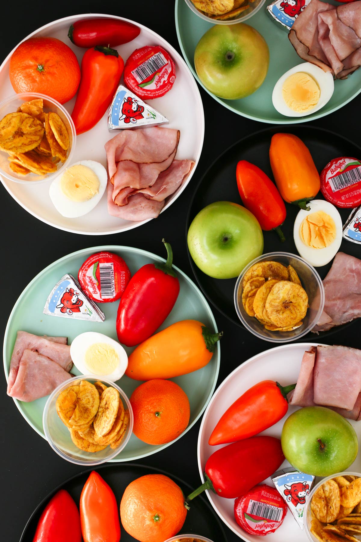 flatlay of small plastic plates with snacks piled on them, like mini charcuterie boards.