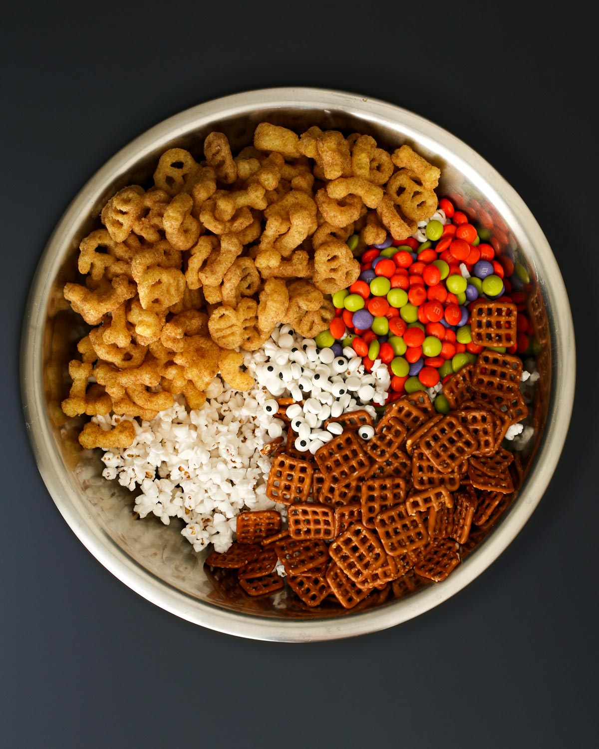 ingredients for halloween snack mix in large mixing bowl.