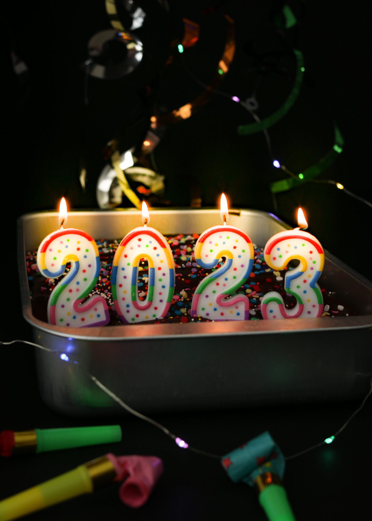 cake decorated with 2023 candles and new year decor and lights.