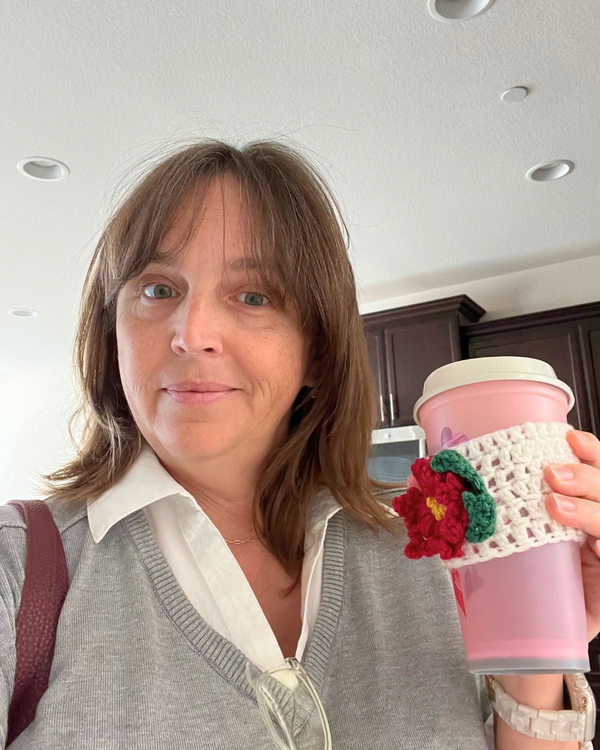 jessica holding a travel cup with styled hair and nice clothes.