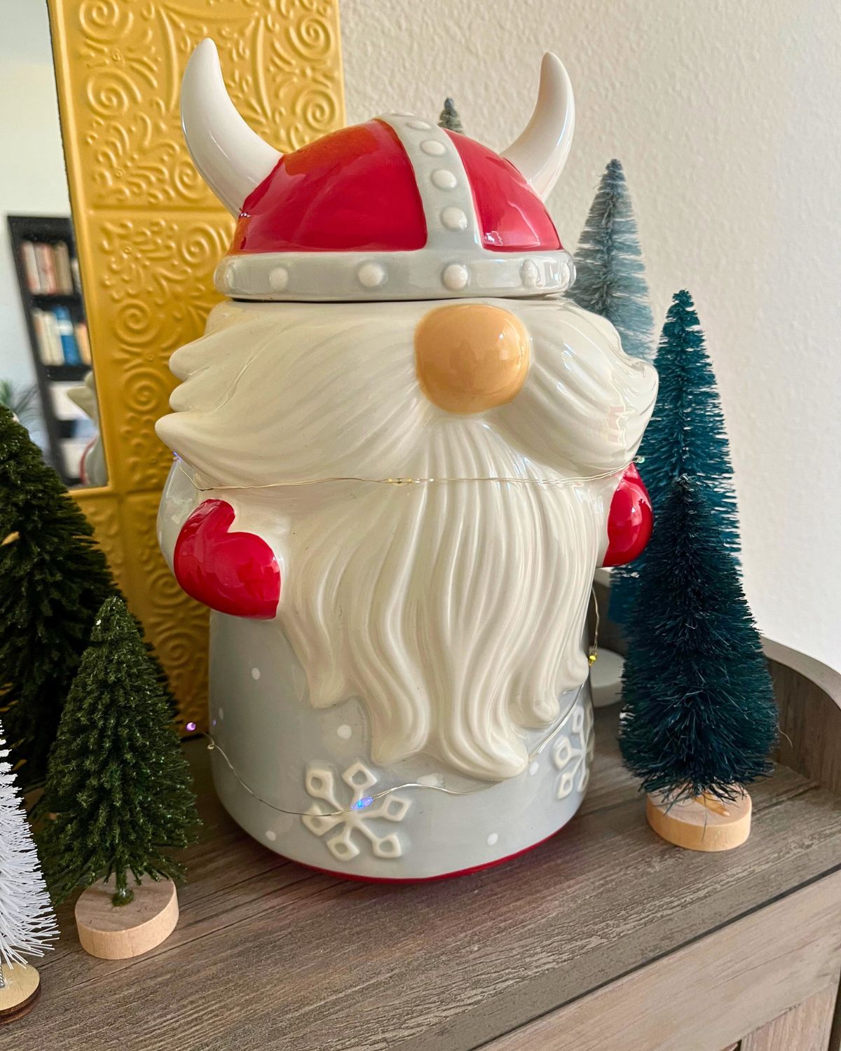 viking santa gnome cookie jar with bottle brush trees on table with mirror behind.