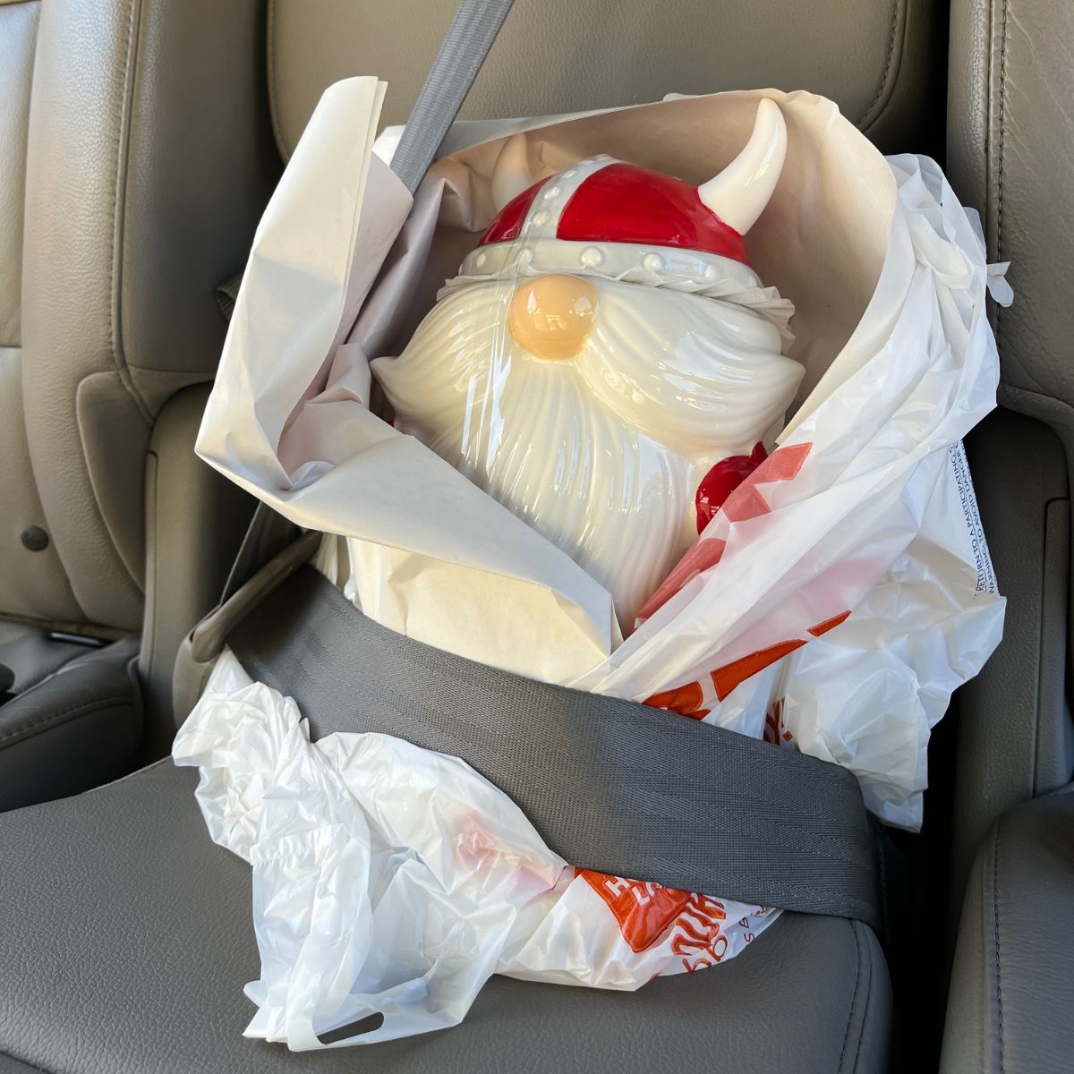 santa gnome cookie jar in  a seat of the car with a seat belt.
