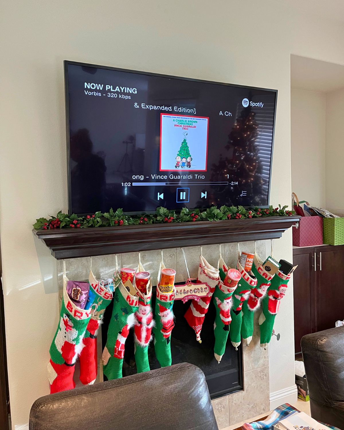 stockings hanging from mantel with charlie brown music playing on spotify.