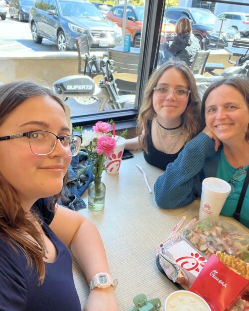 the girls and I at chick-fil-a with lunch on table.