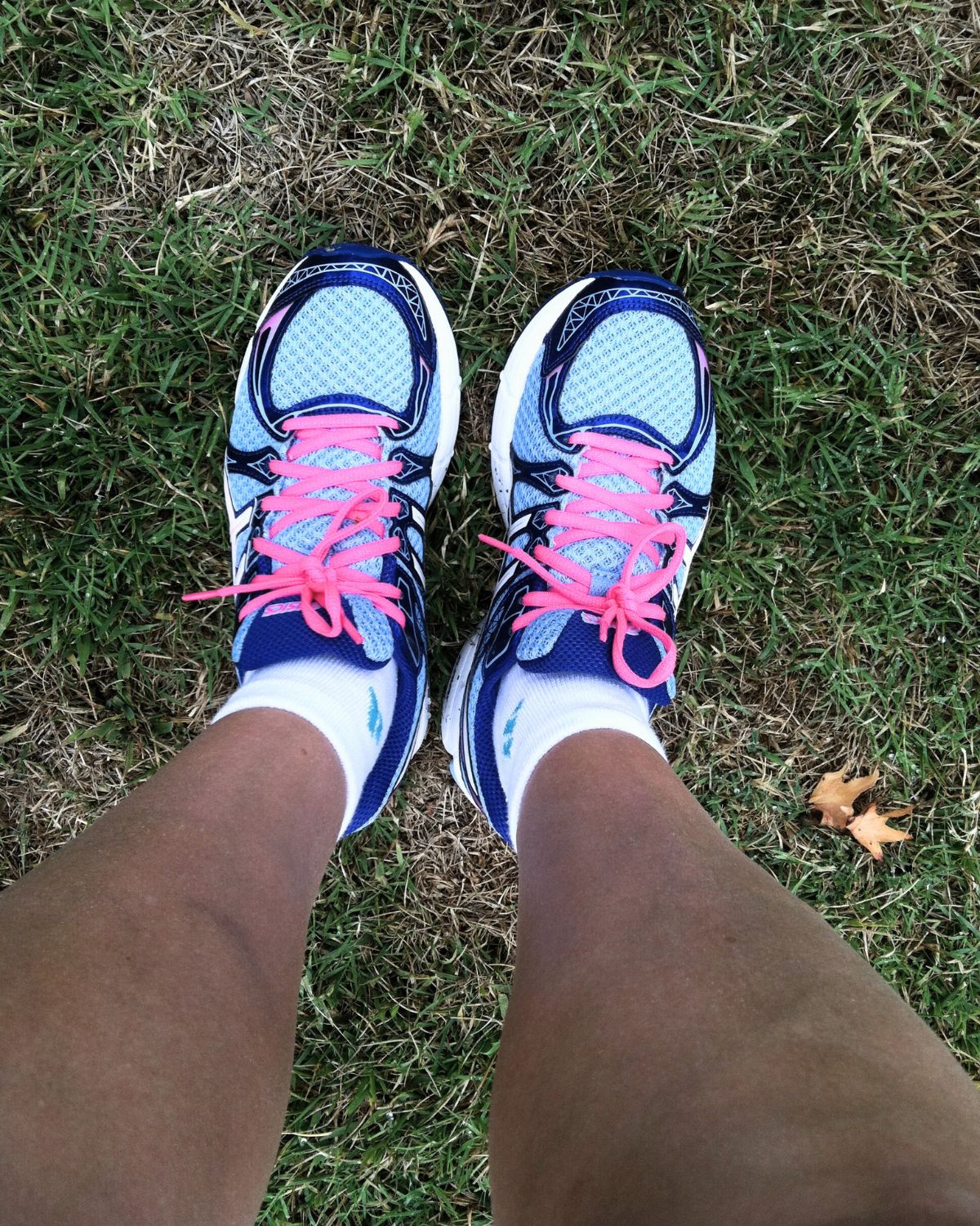 looking down at feet in new running shoes on grass.