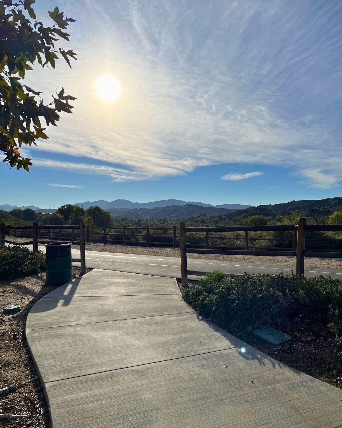 a walking path heading toward the sun and blue skies overhead.