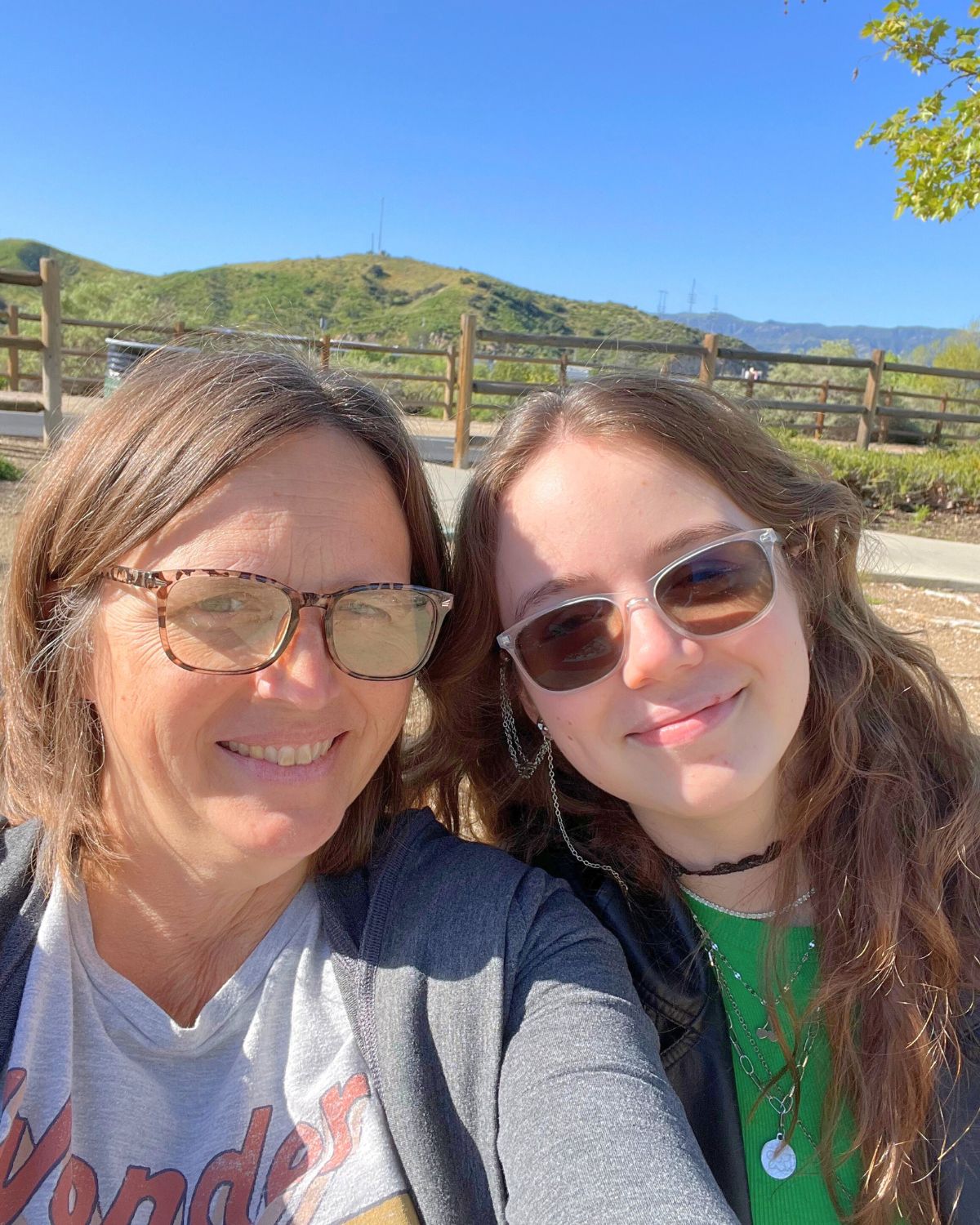 jessica and fishchick15 in the sun with hill and blue sky behind.