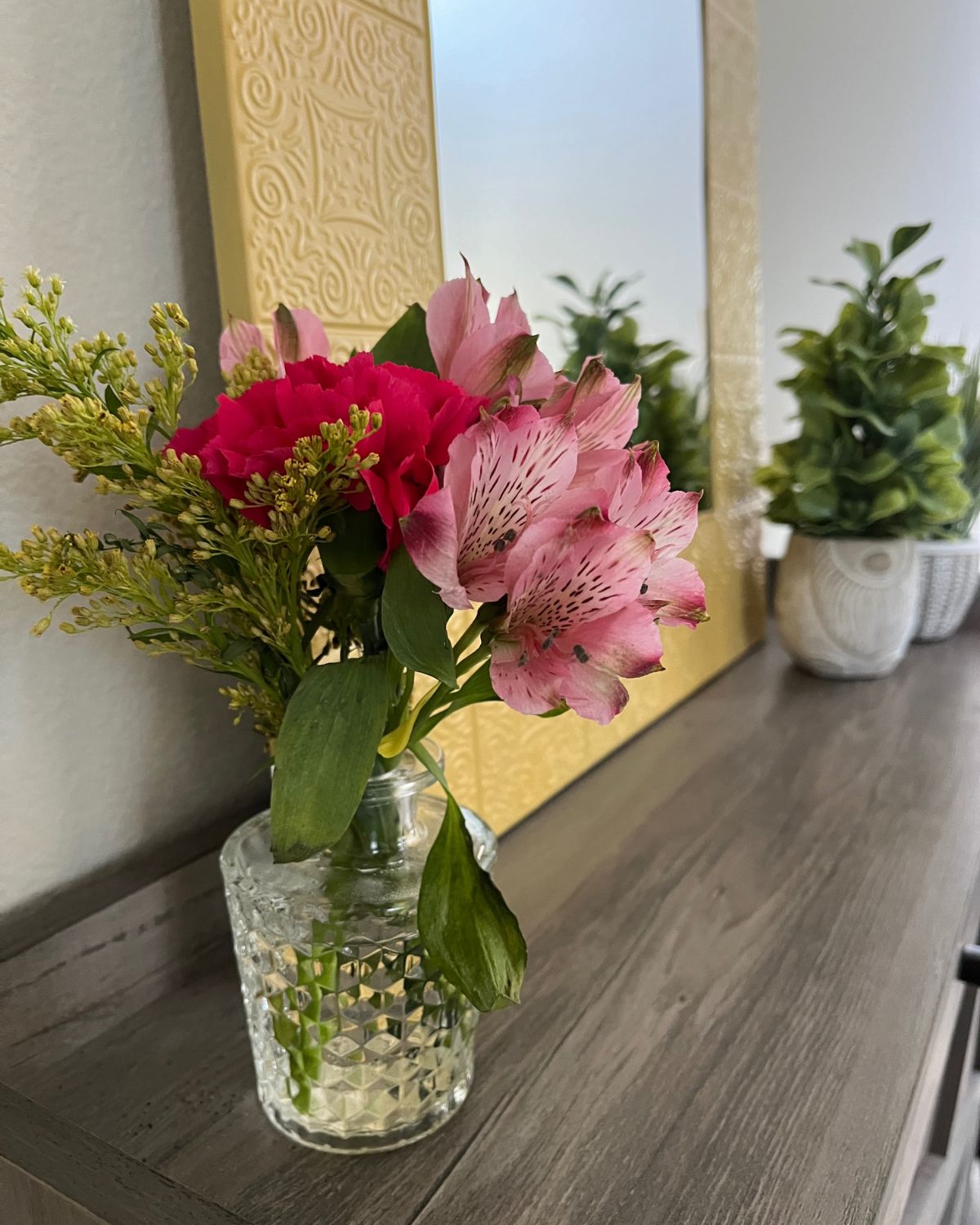 bouquets of flowers by mirror in entryway.