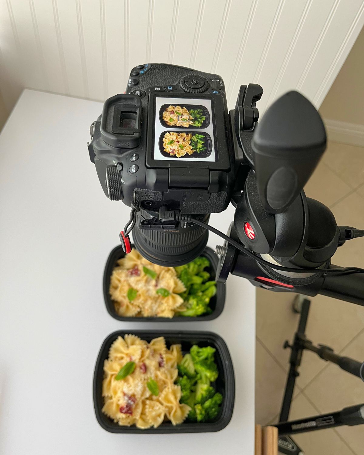 camera shooting a picture of meal prep pasta on a white table.