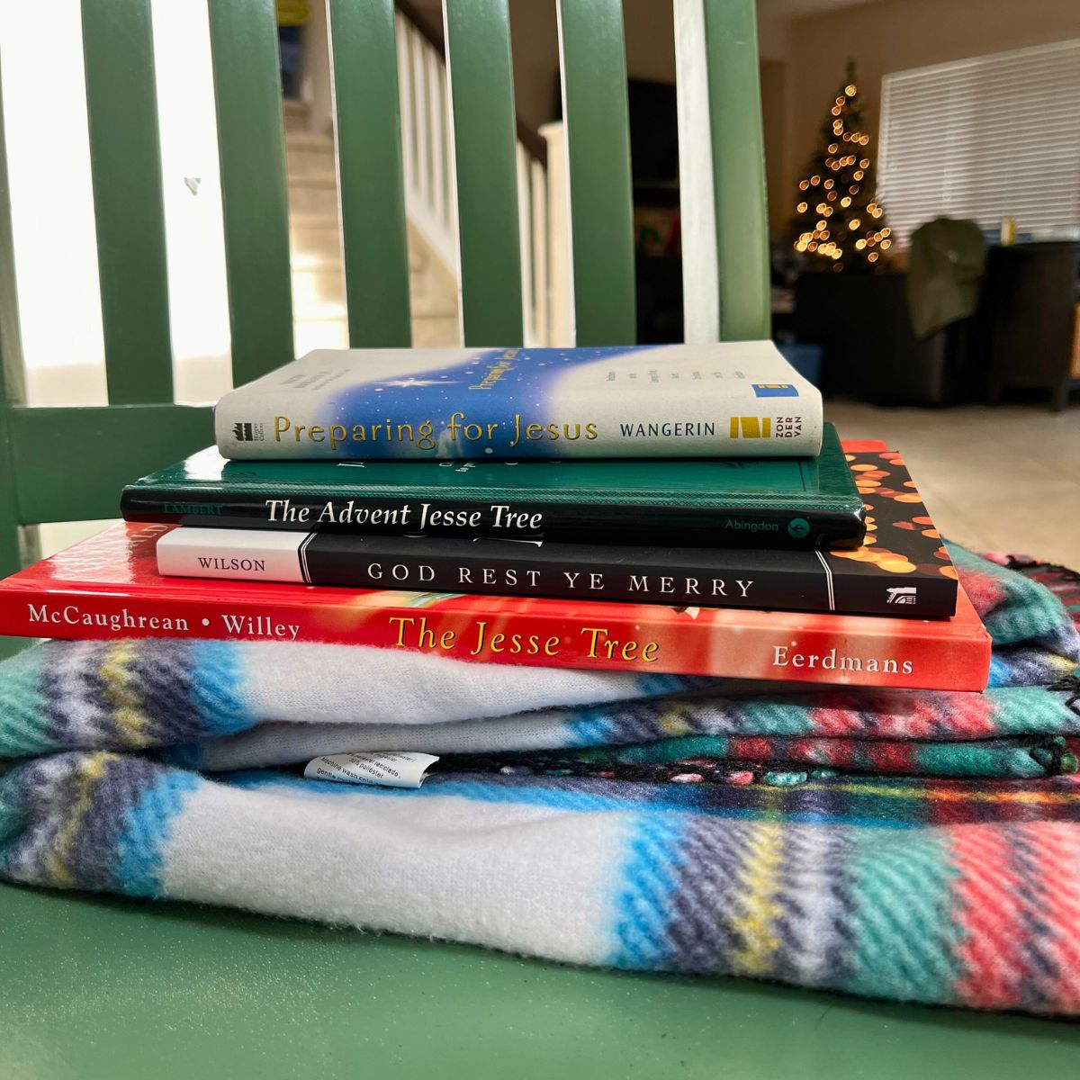 stack of advent devotionals on a plaid blanket on a green chair.