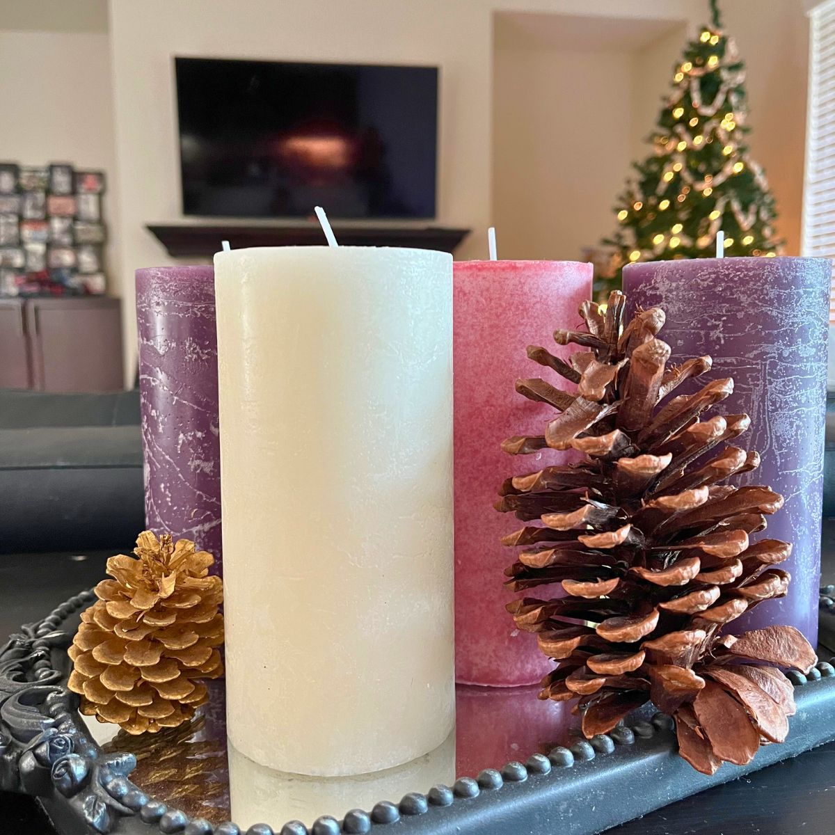 pillar advent candles with pine cones on a tray.