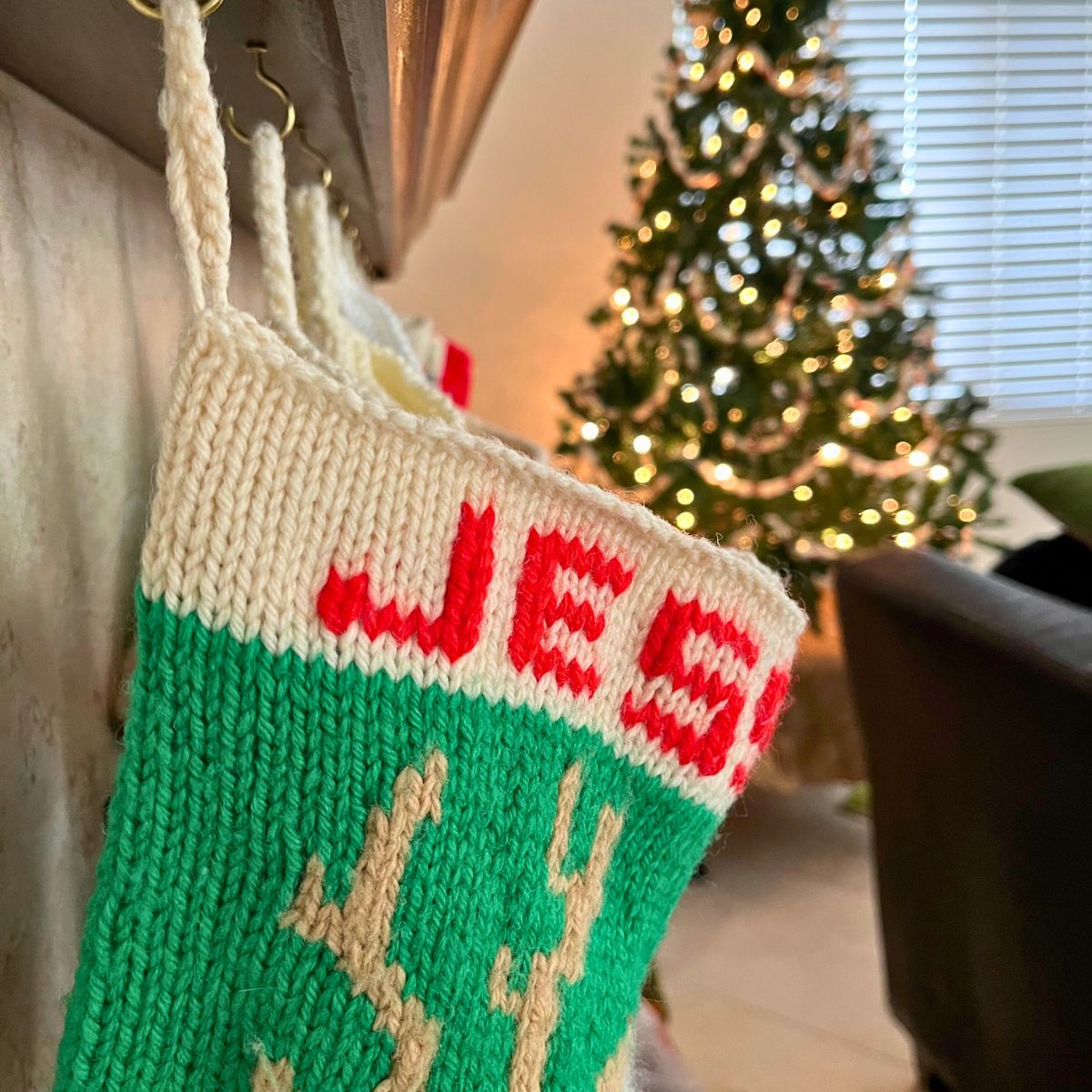 line of stockings hanging on mantle with christmas tree in the distance.