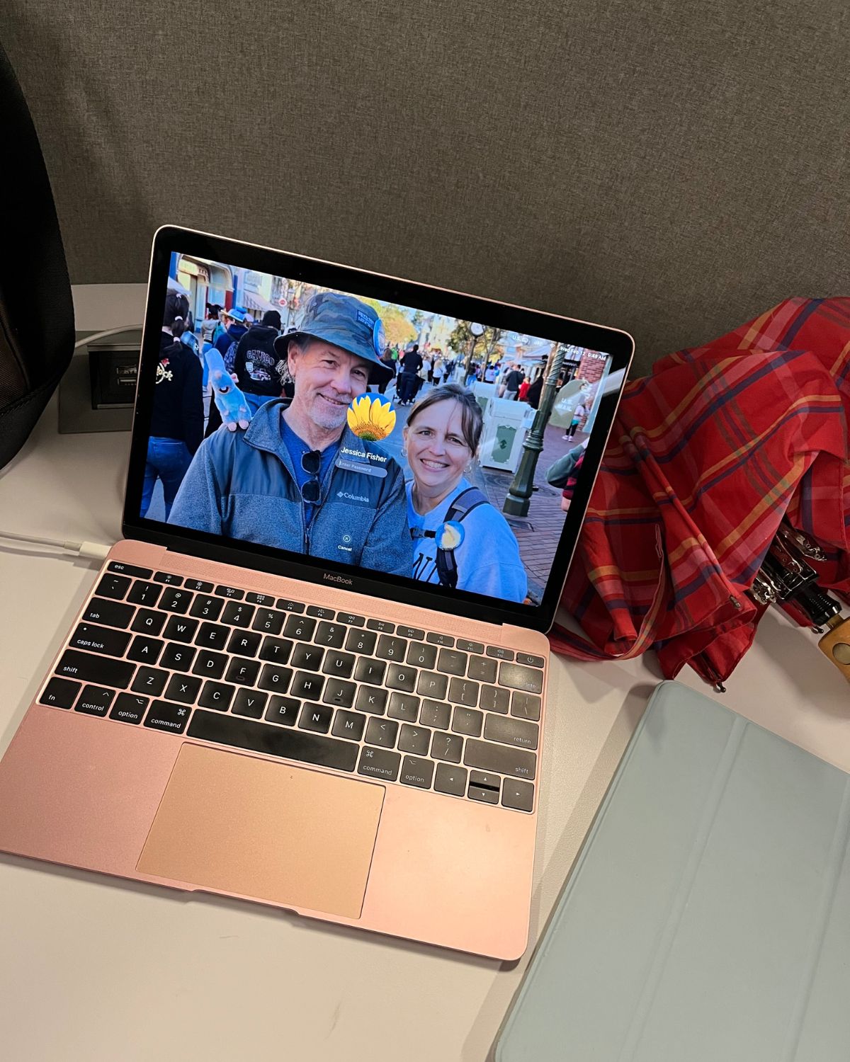 open laptop on desk at library with picture of bryan and jessica as the wallpaper, umbrella nearby.