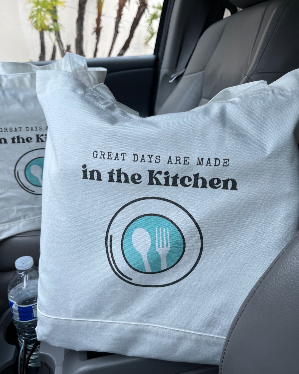 cloth bag on car seat, with good cheap eats logo and words, great days are made in the kitchen.