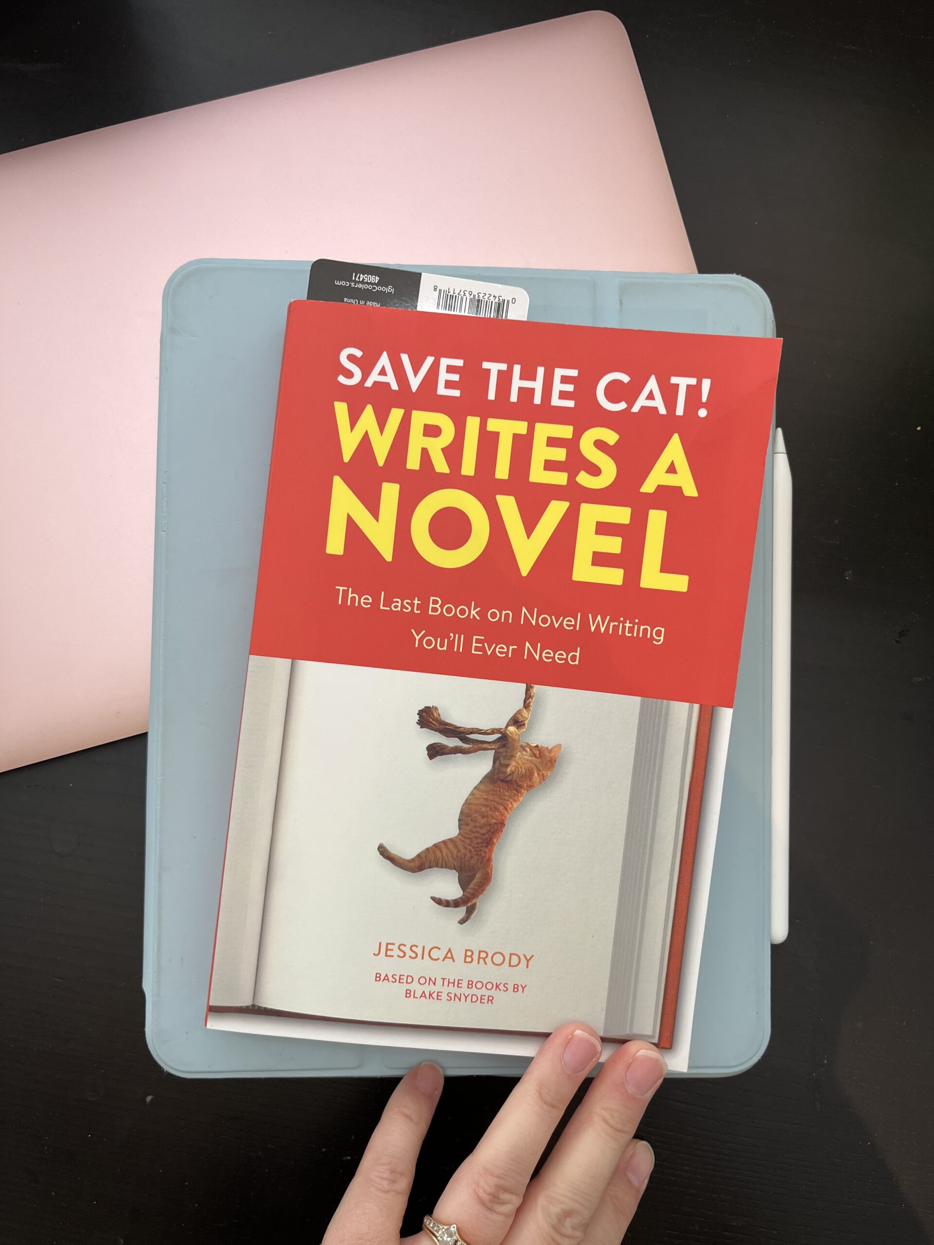 Save the cat writes a novel book atop tablet and computer.