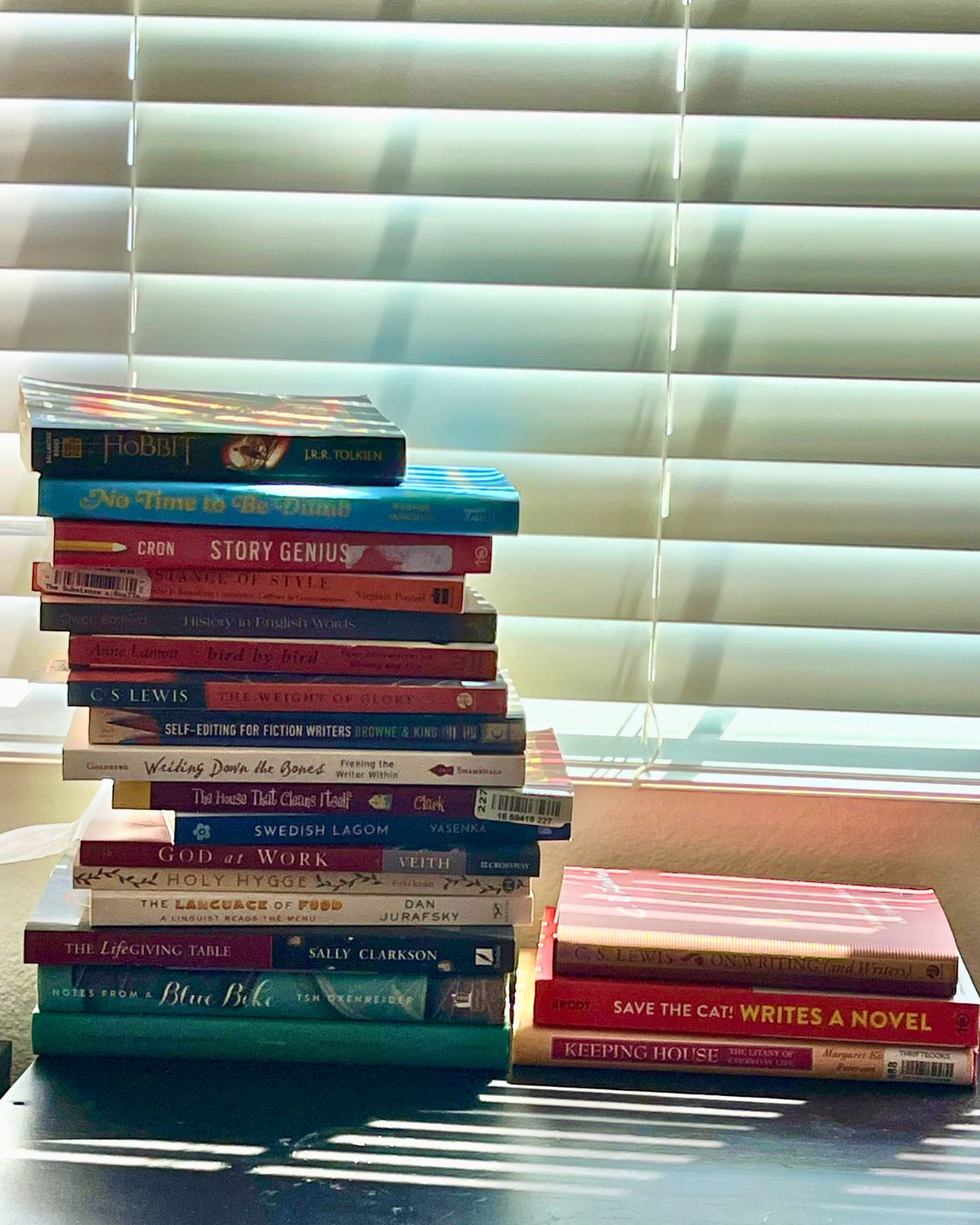 stacks of books on black table by the blinds.