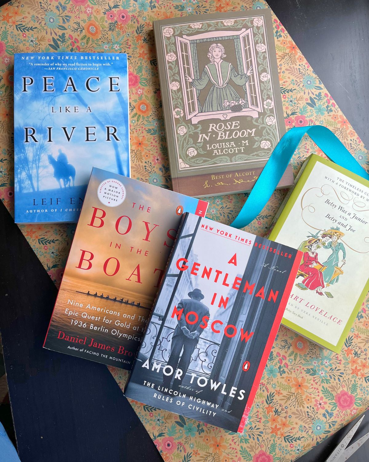 array of easter books on flowered wrapping paper with teal ribbon.