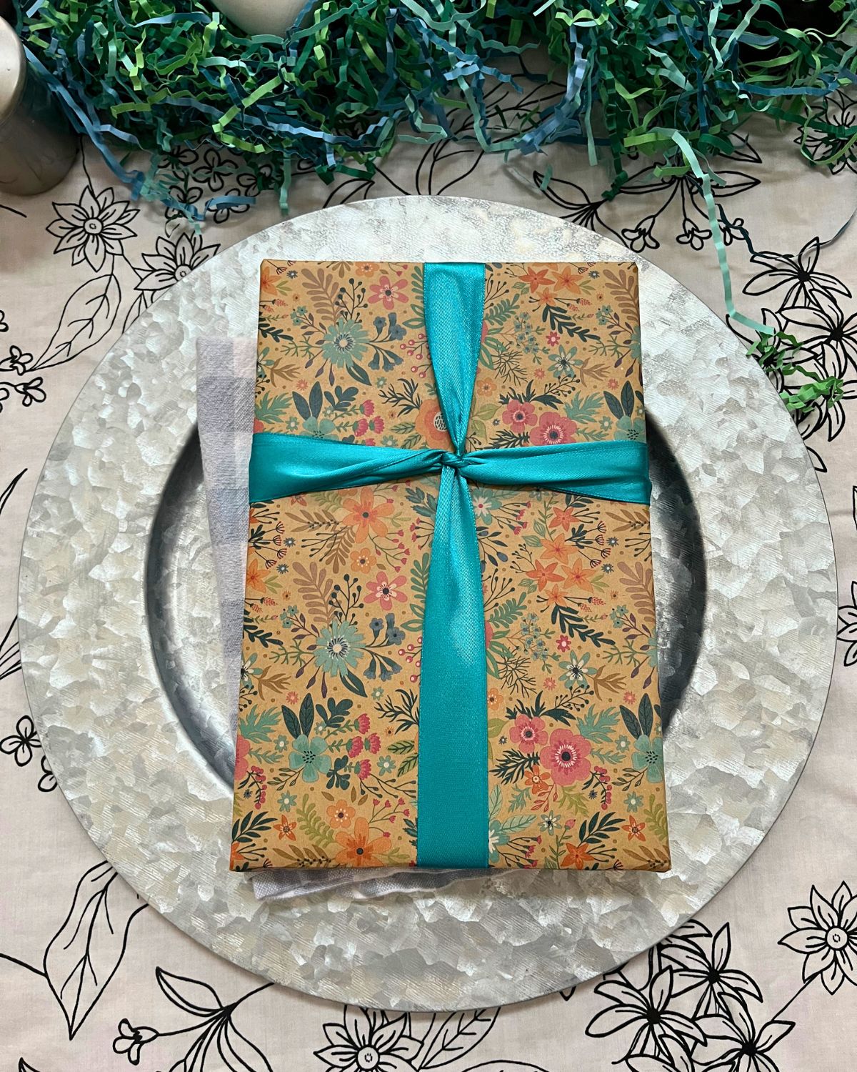 wrapped present on charger with cross shaped ribbons.