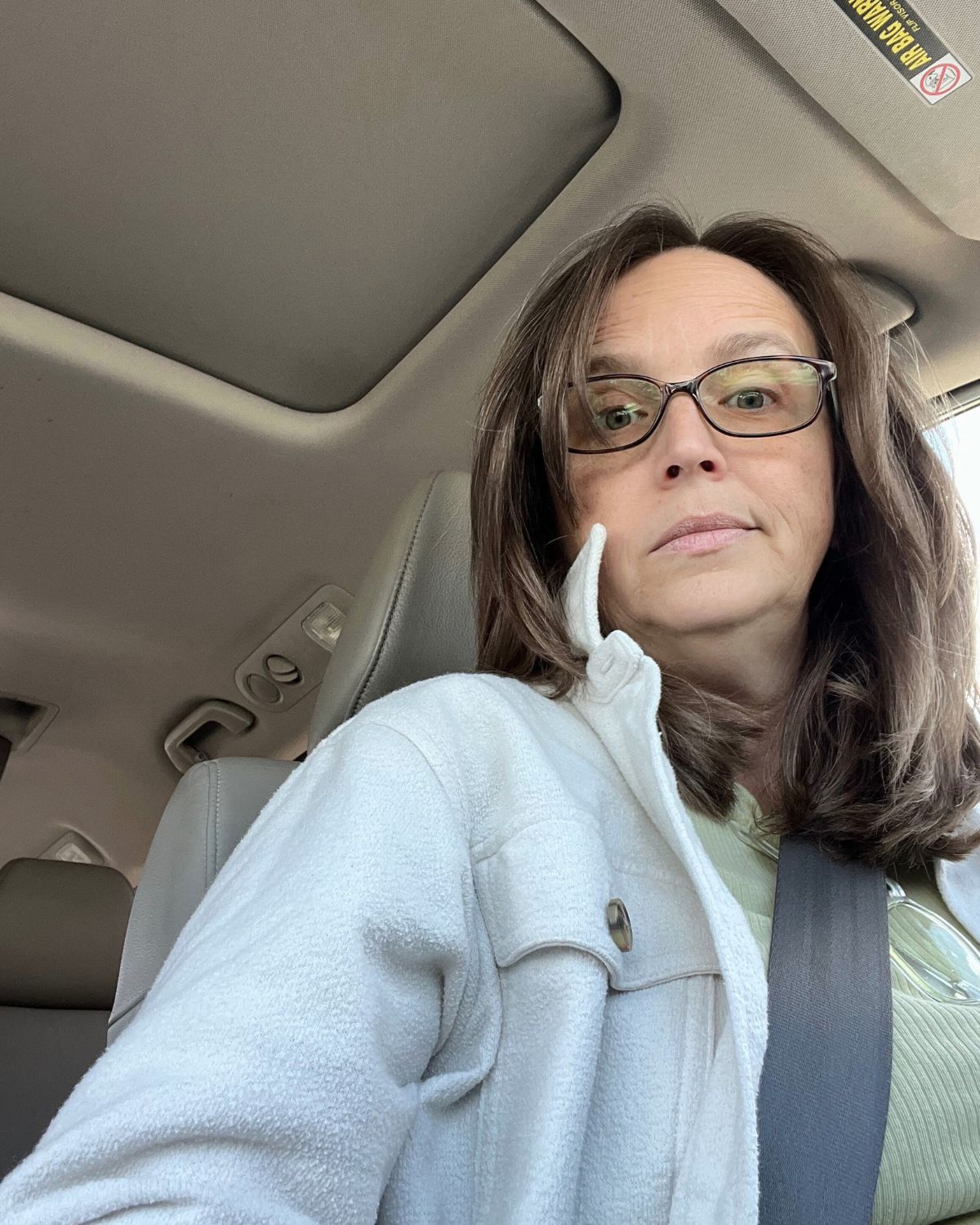 jessica looking down phone from driver's seat of van.