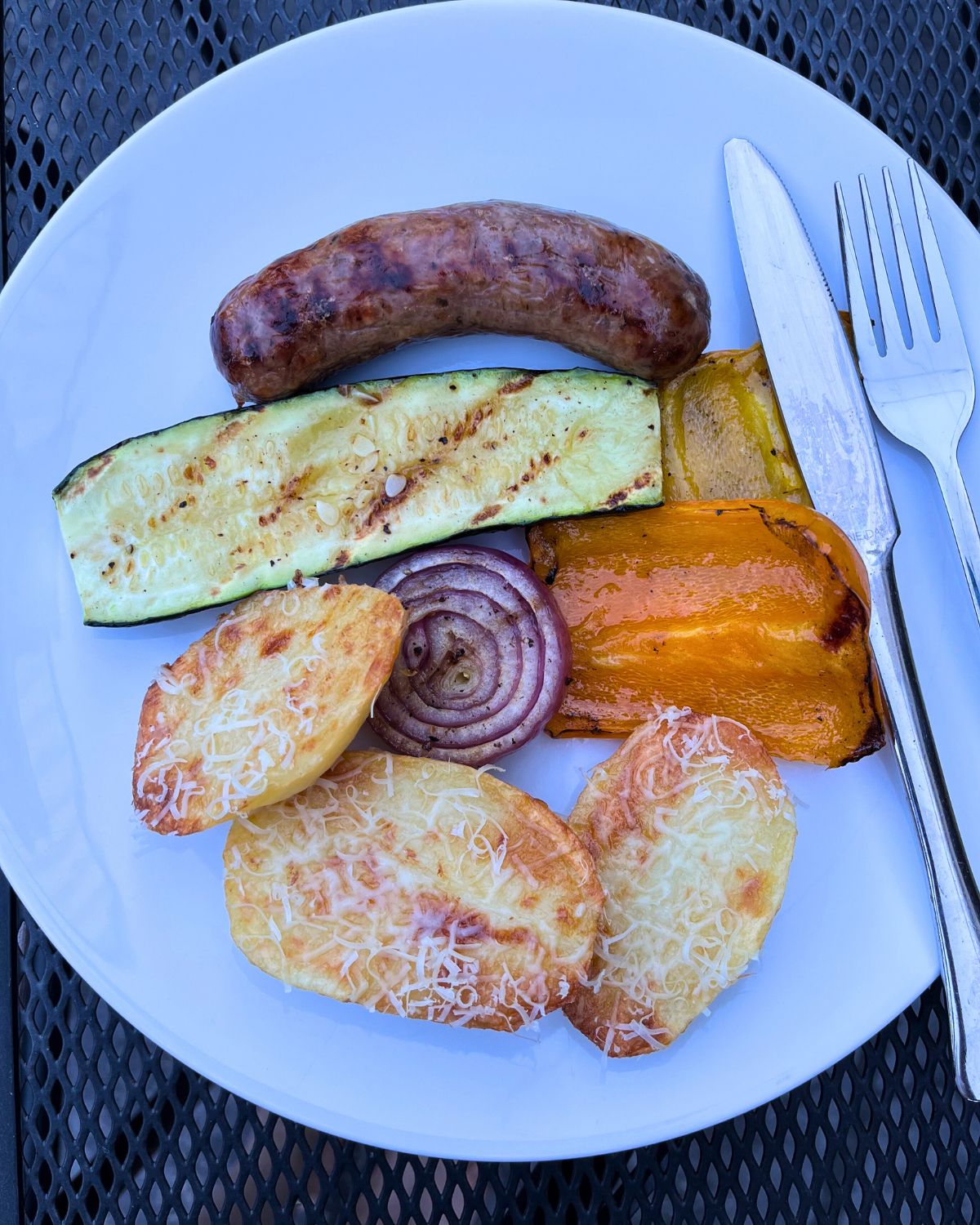 dinner plate of roast potatoes, grilled veg, and sausage.