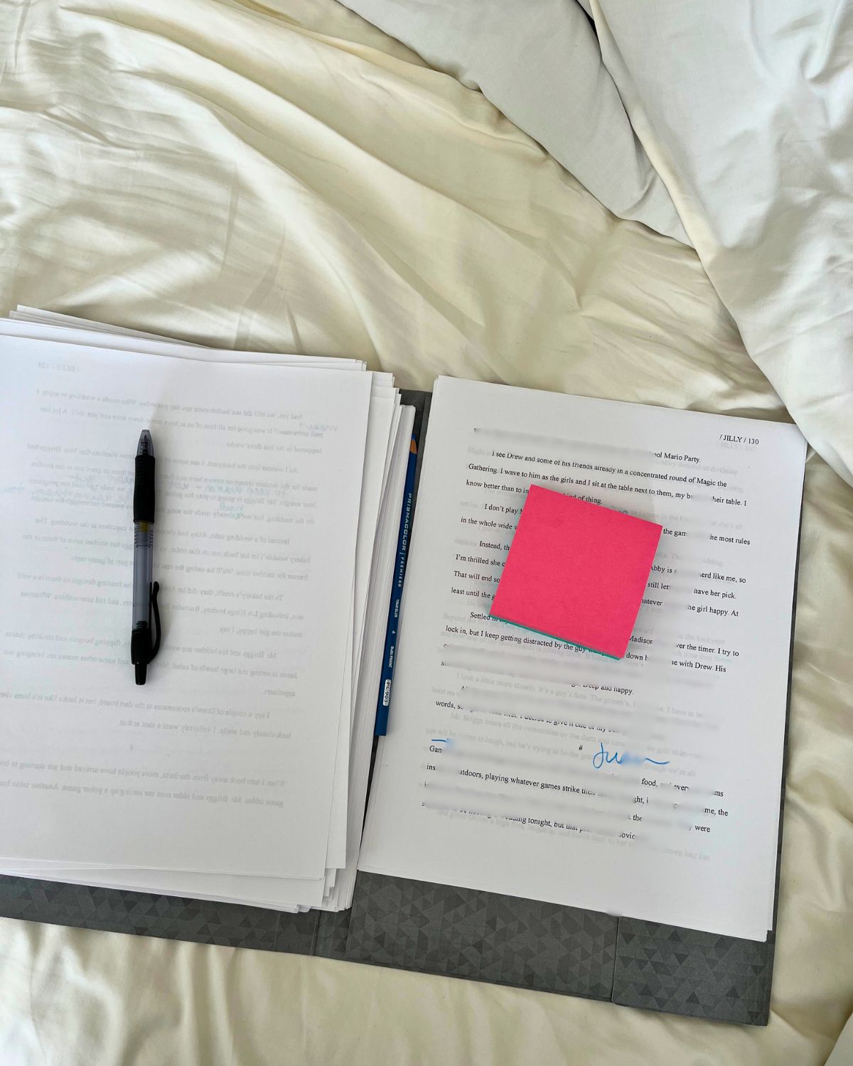 printed draft of my book on the sheets of my bed with post-its and pen.