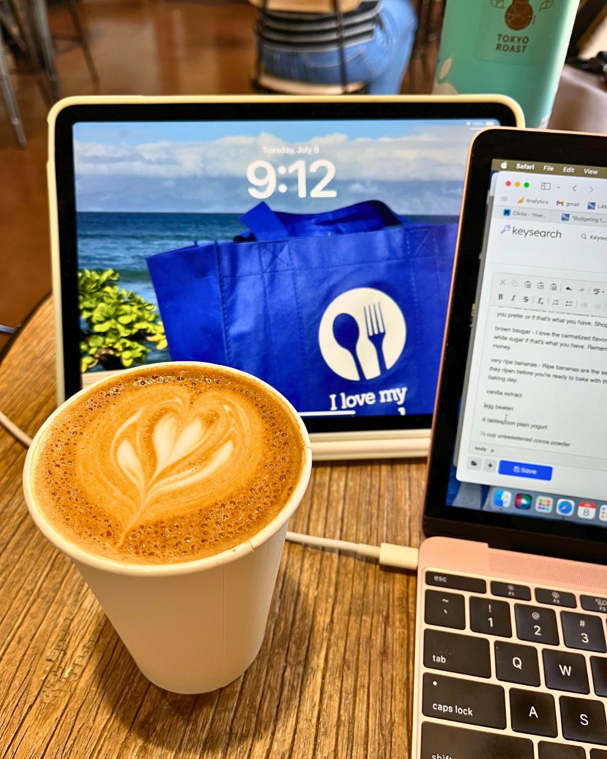 iPad, laptop, and flatwhite on cafe table.