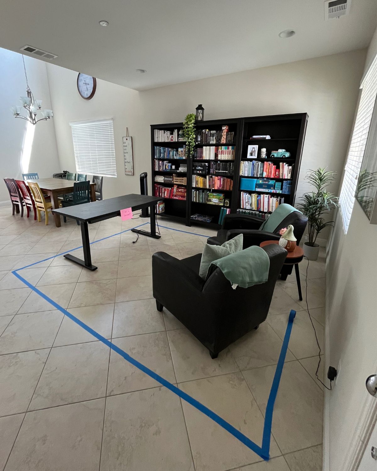 front room with blue tape marking where the rug could go, bookcases, and a pretend loveseat.