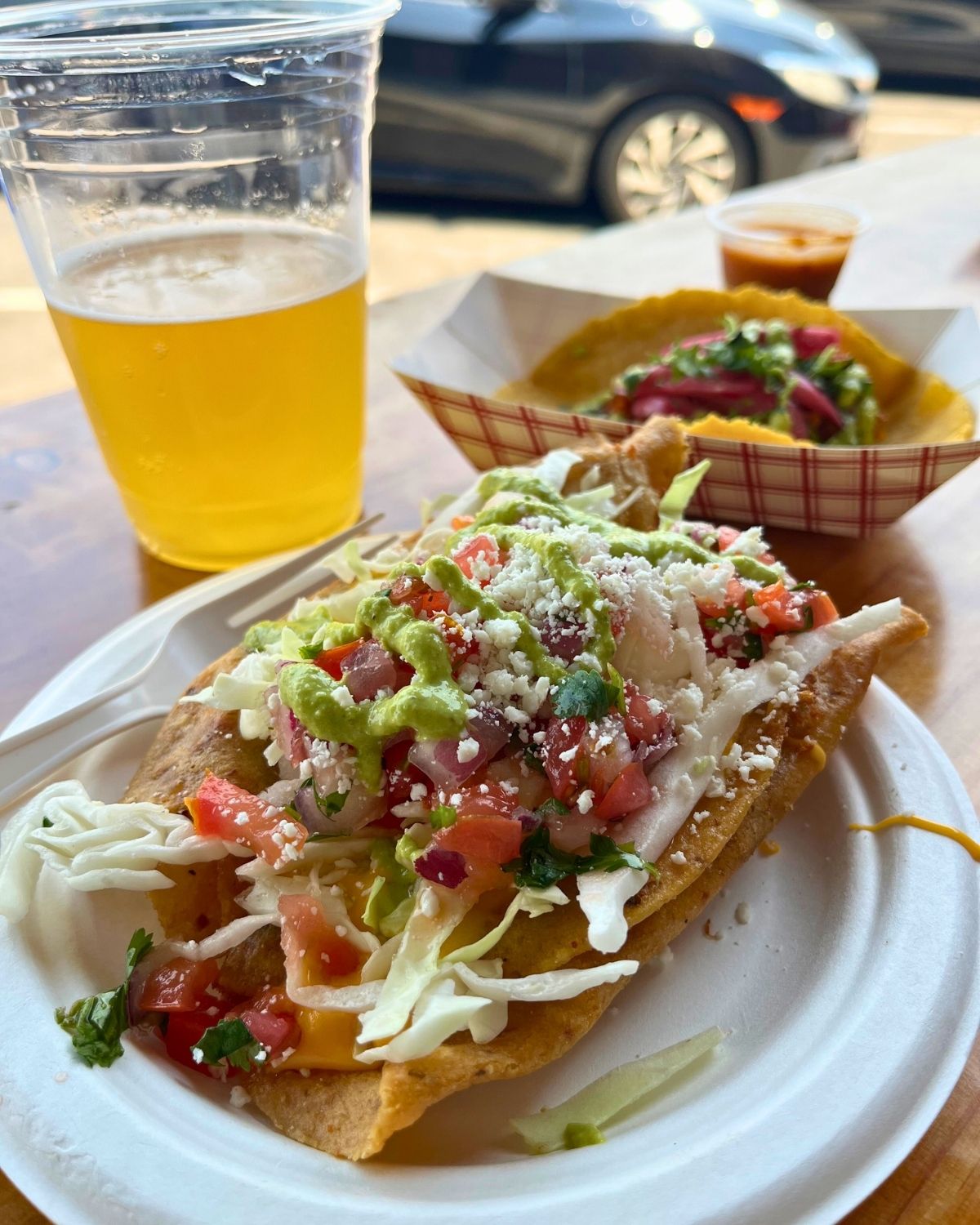 two plates of tacos from city taco plus a cold beer on counter facing street.
