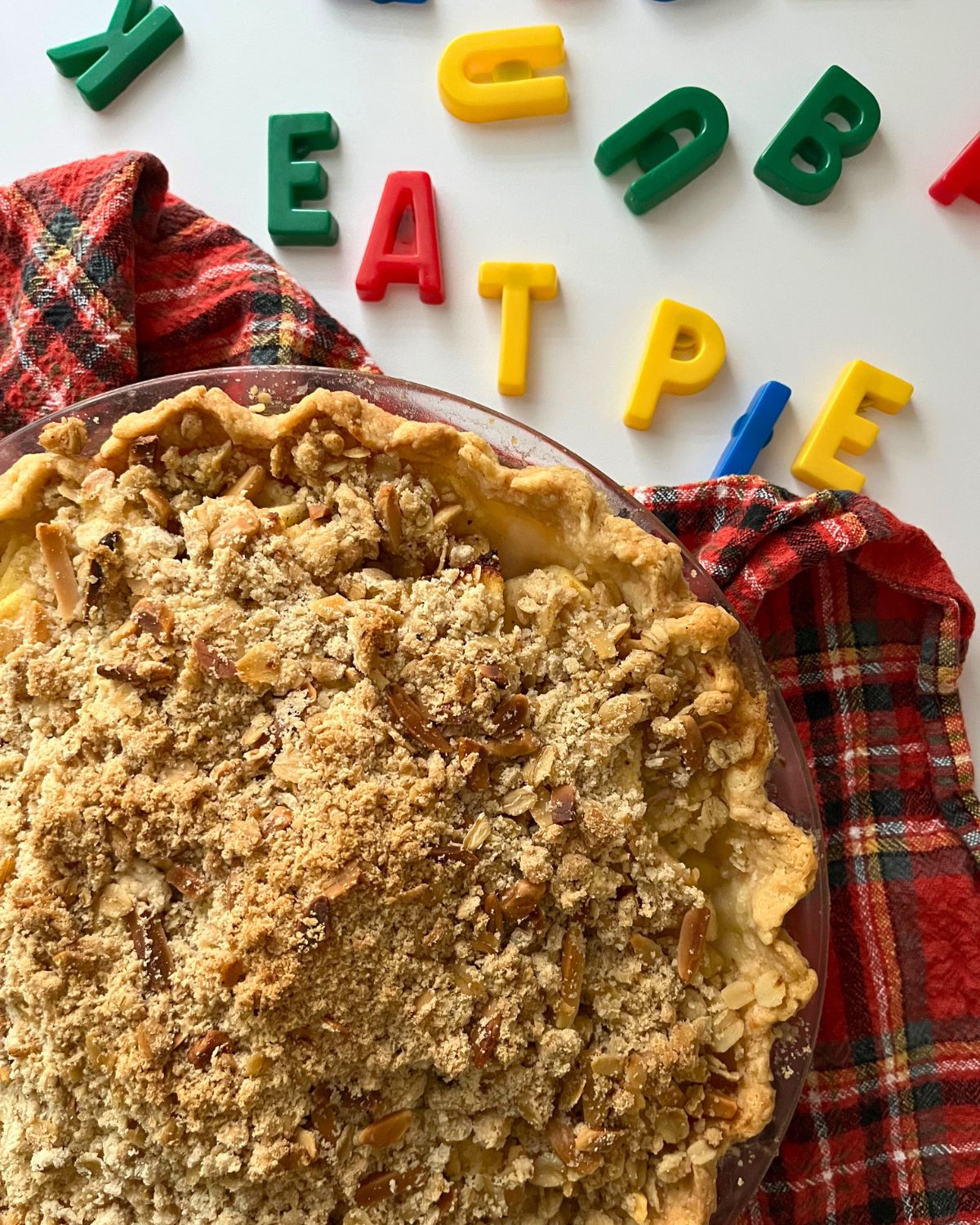 apple crumb pie on red plaid cloth with letter magnets spelling out eat pie.