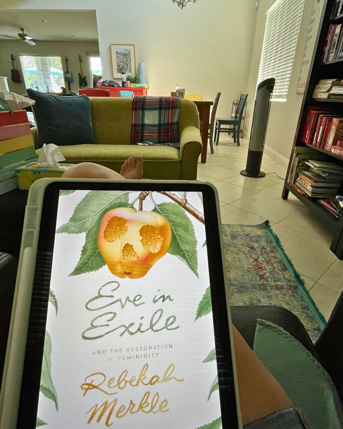 eve in exile on iPad with living room in background.