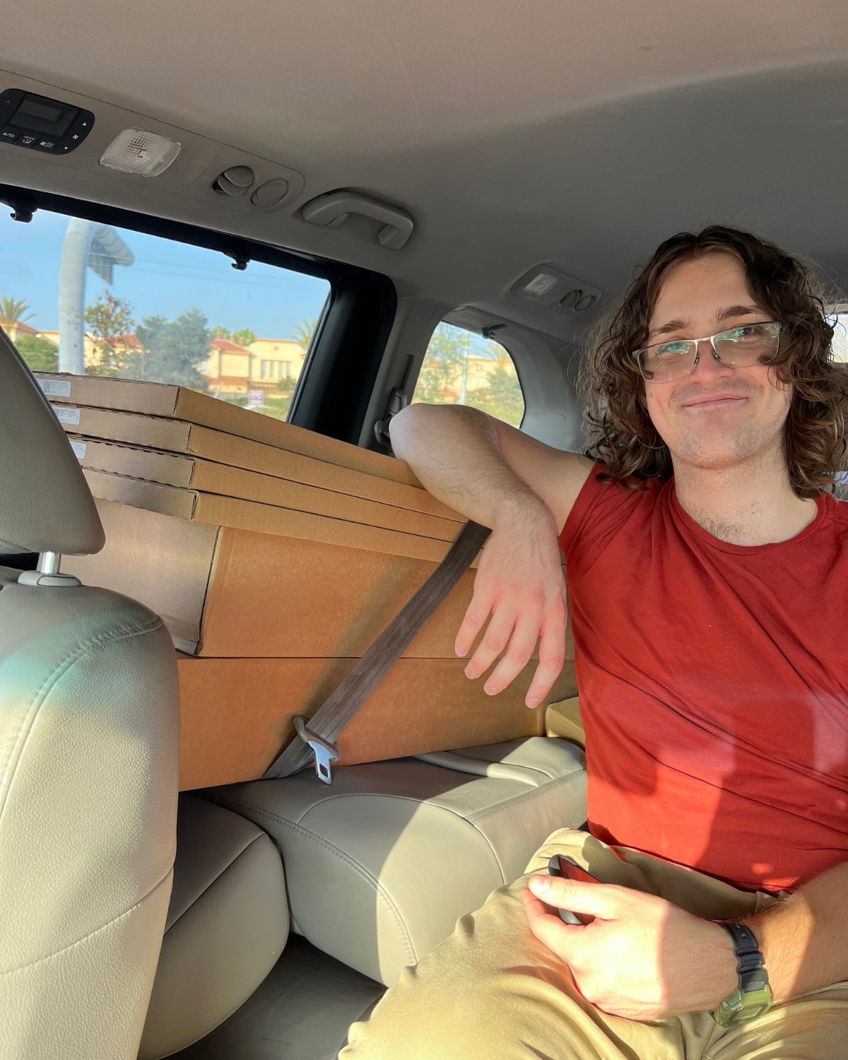ikea boxes crammed into mini van with young man resting his arm on the top of the stack from the middle seat.