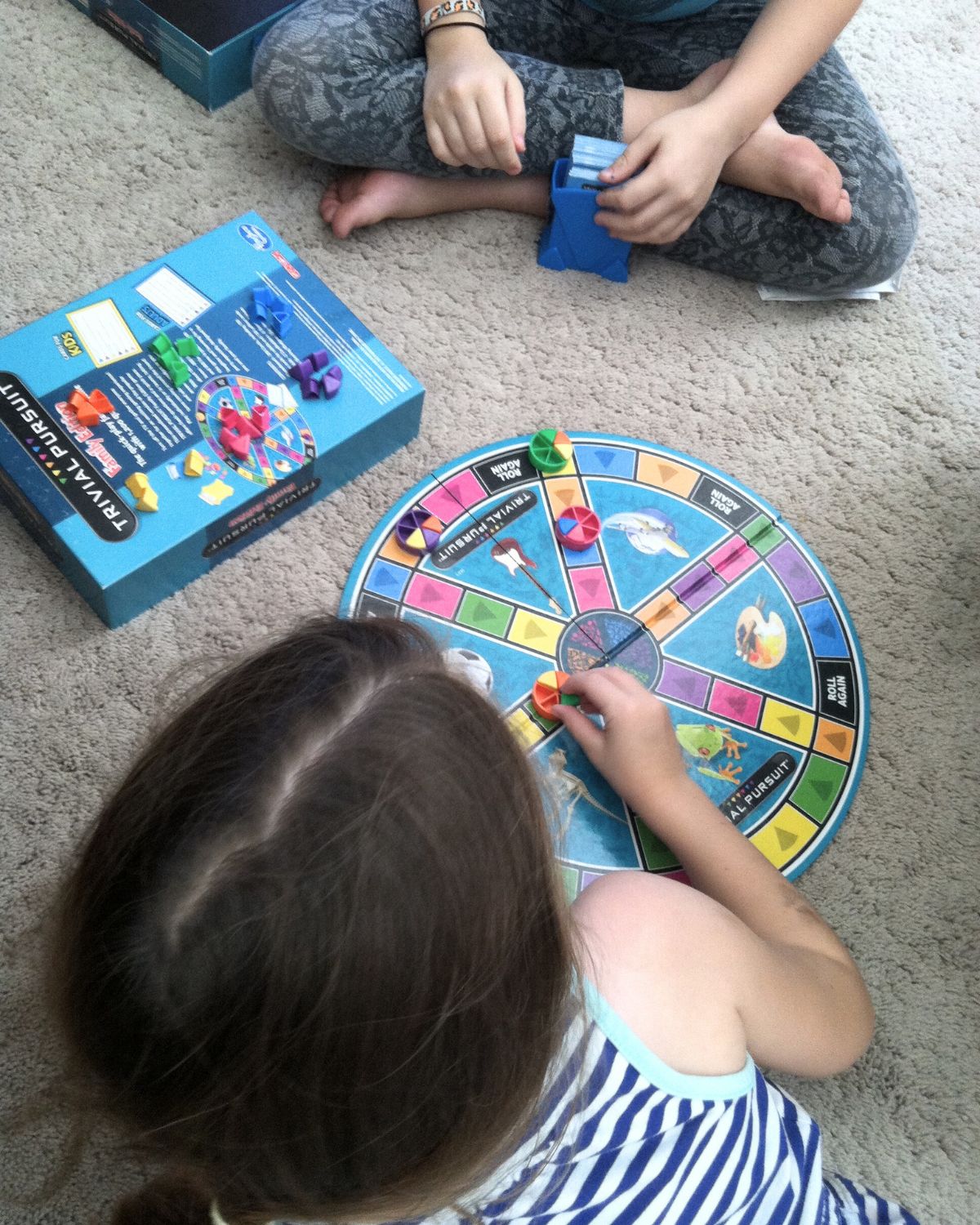 kids playing trivial pursuit on carpet.