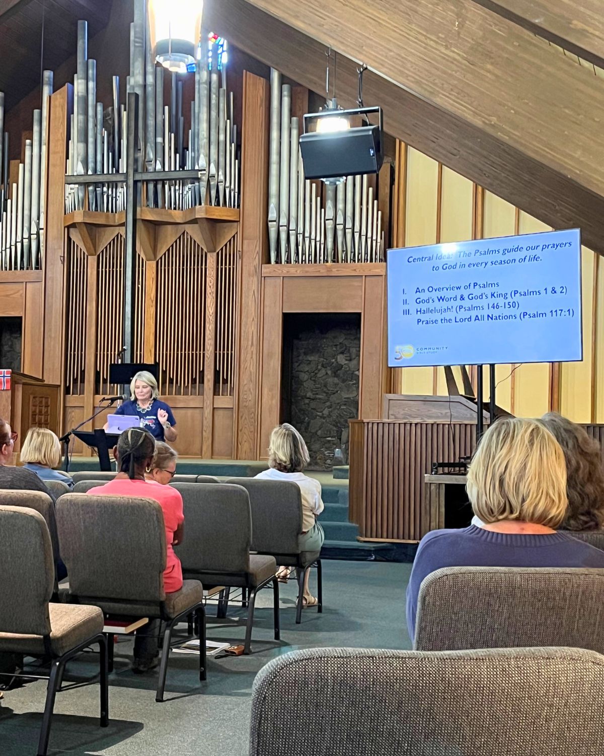 a picture of cbs speaker and screen in church with organ pipes in background.