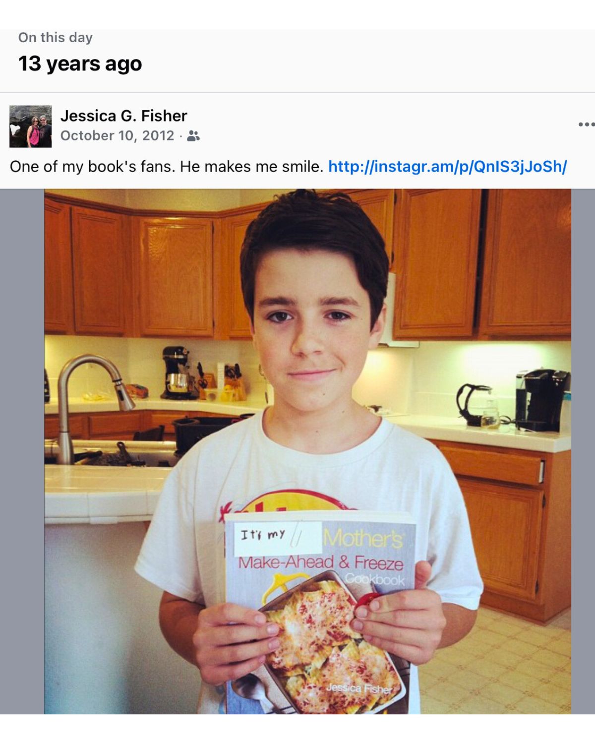 boy holding cookbook in kitchen.