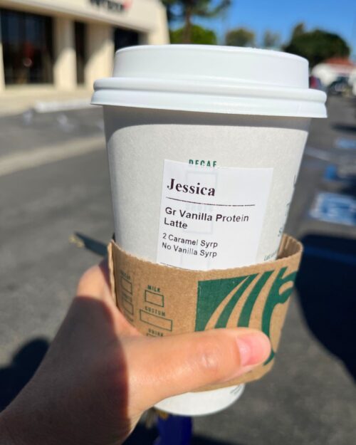 holding a protein latte with the blue sky in the background.