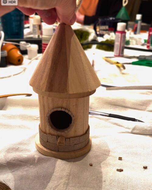 laying brick on a round turret birdhouse.