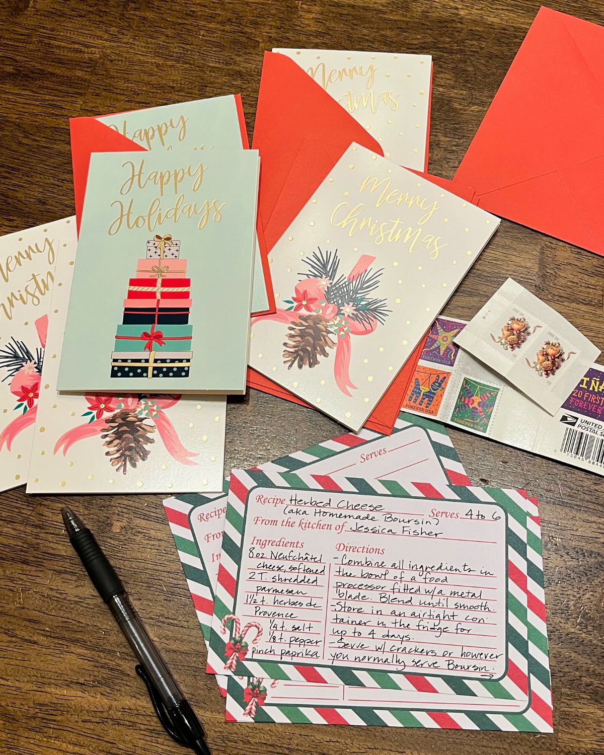 array of christmas cards and recipes card on wooden table with pen and stamps.
