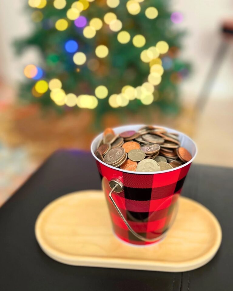 plaid bucket of coins by a lit christmas tree.