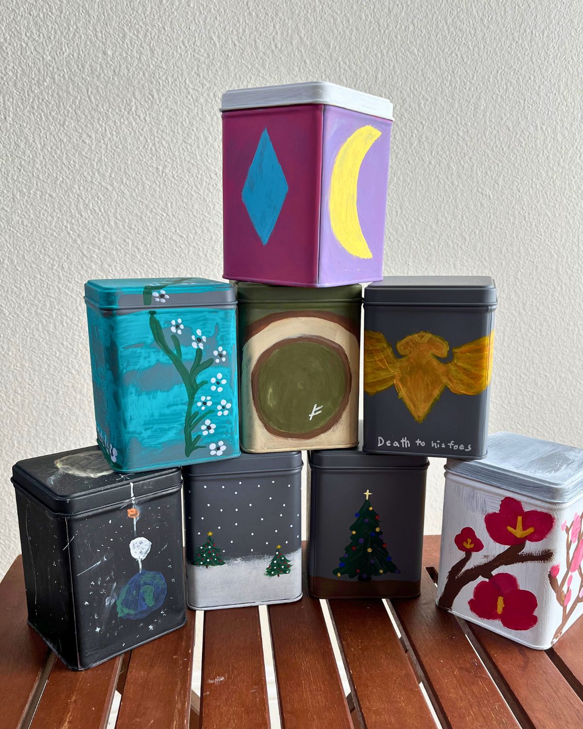 tea tins stacked on a wood table with a white background.